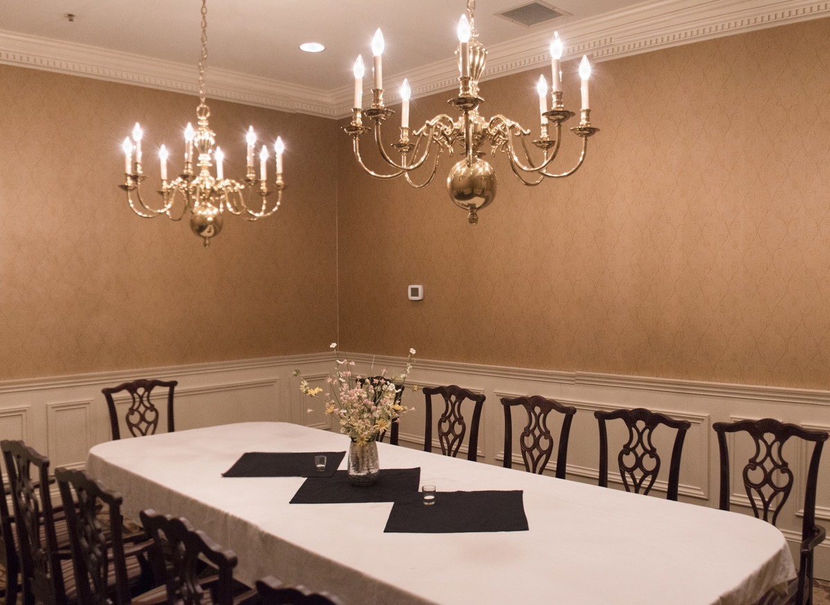 a chandelier over a table with chairs and flowers