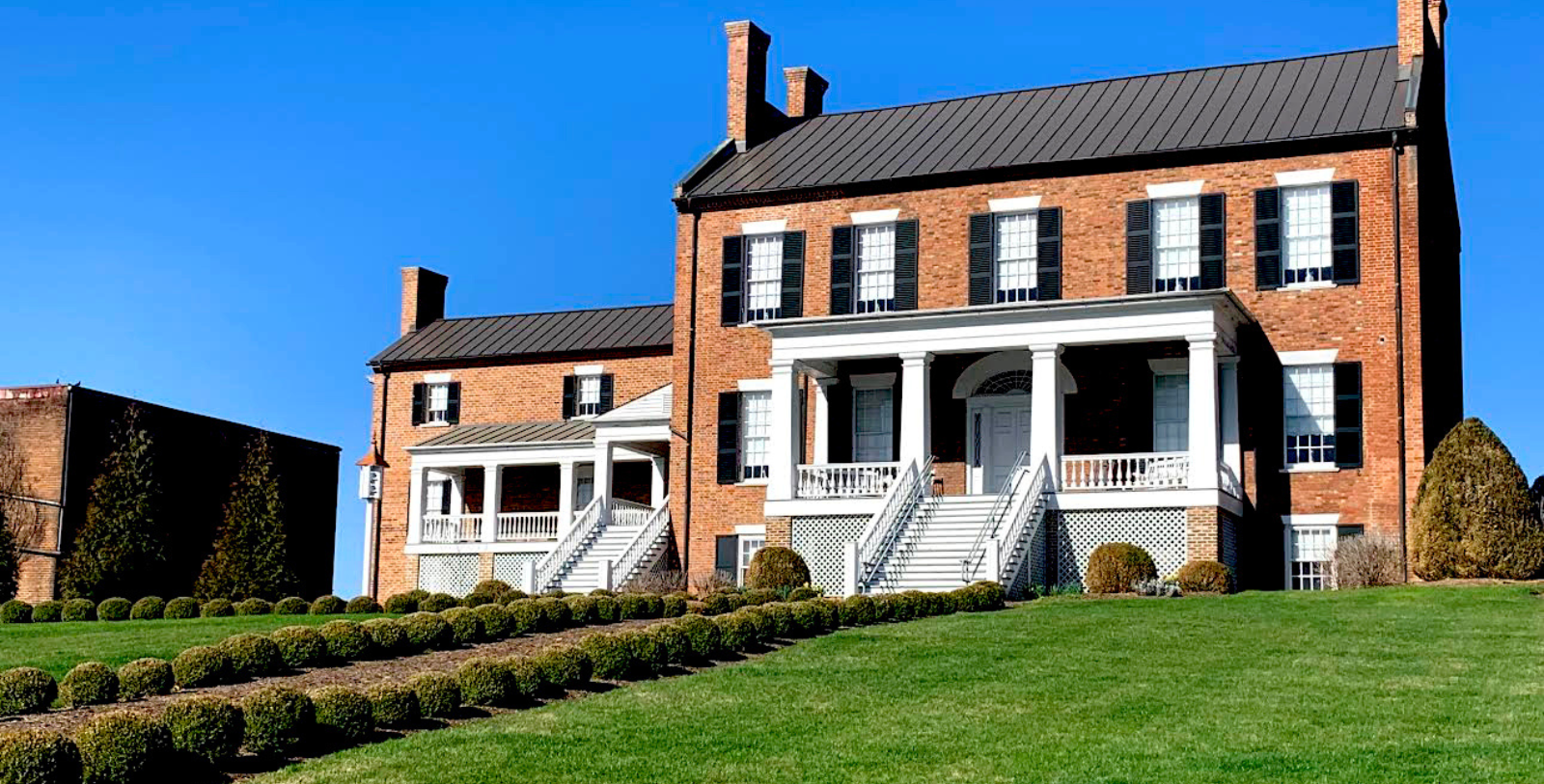 a brick building with white columns and a lawn