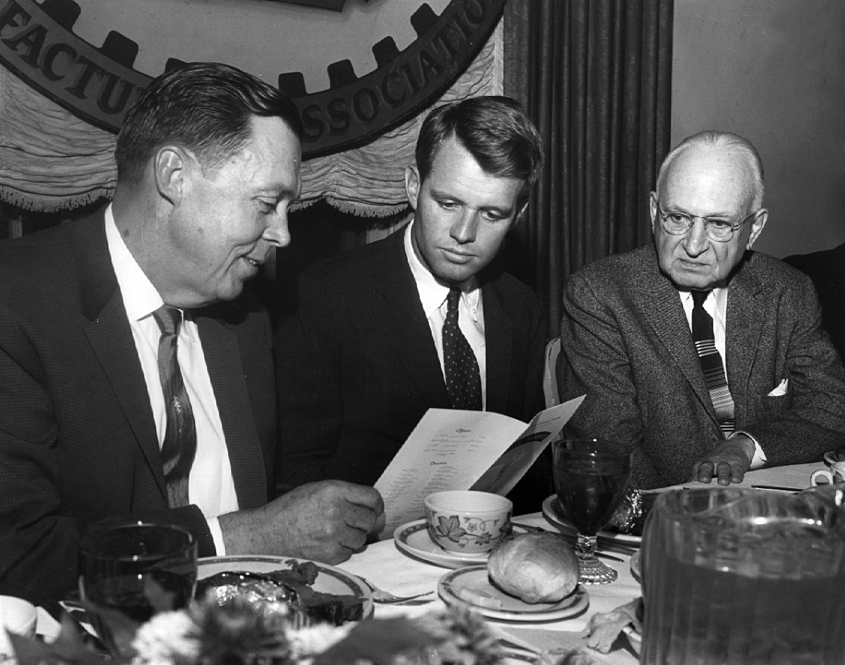 a group of men sitting at a table looking at a menu