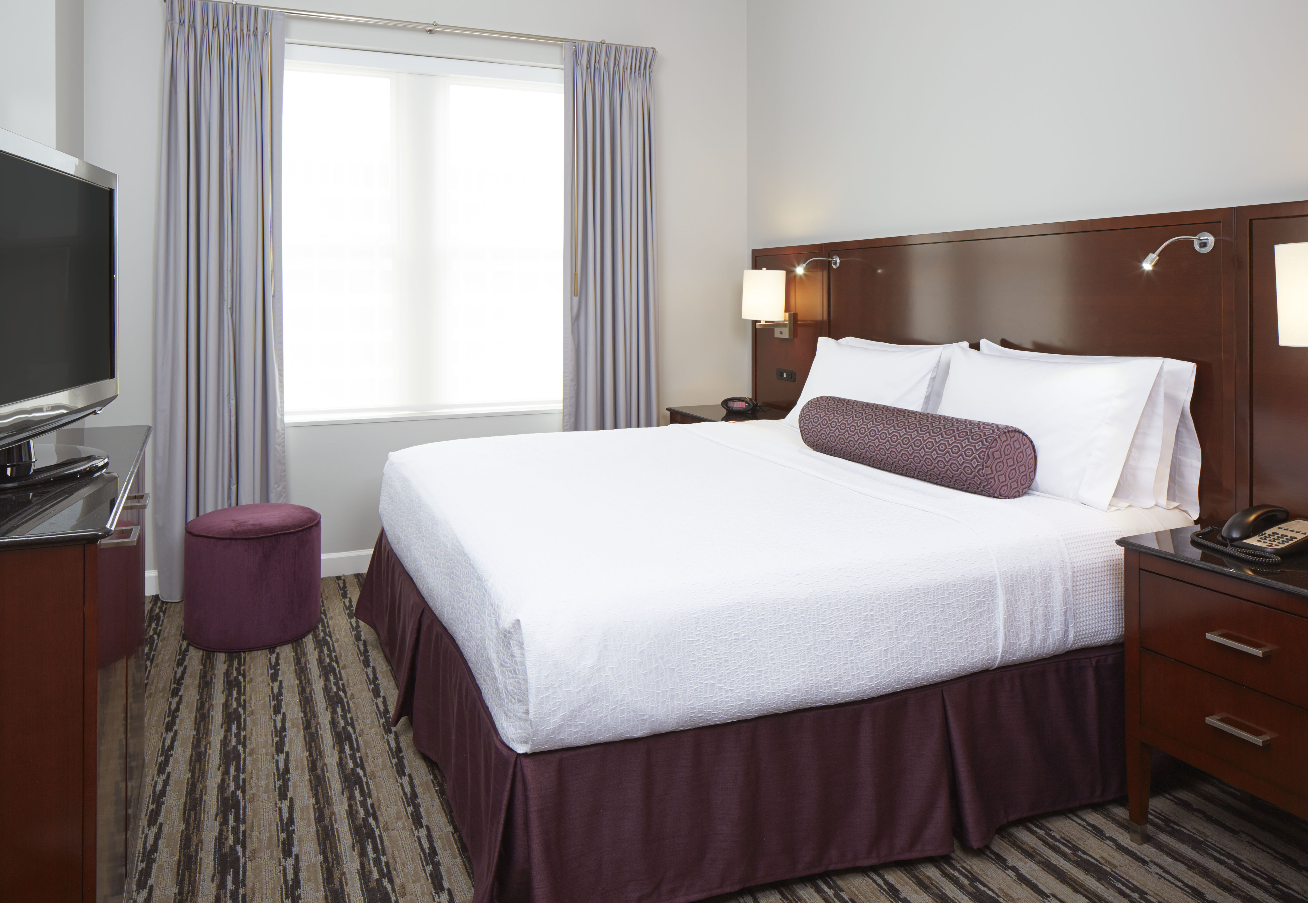 a bed with a purple bed skirt and a purple ottoman