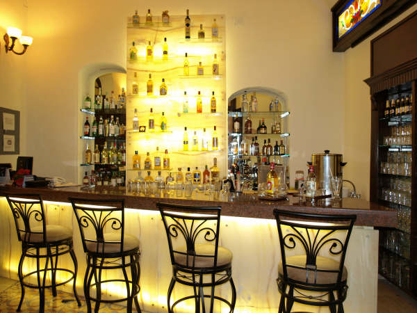 a bar with a row of chairs and a shelf with liquor bottles
