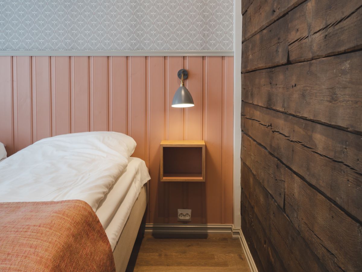 a lamp on a shelf next to a bed