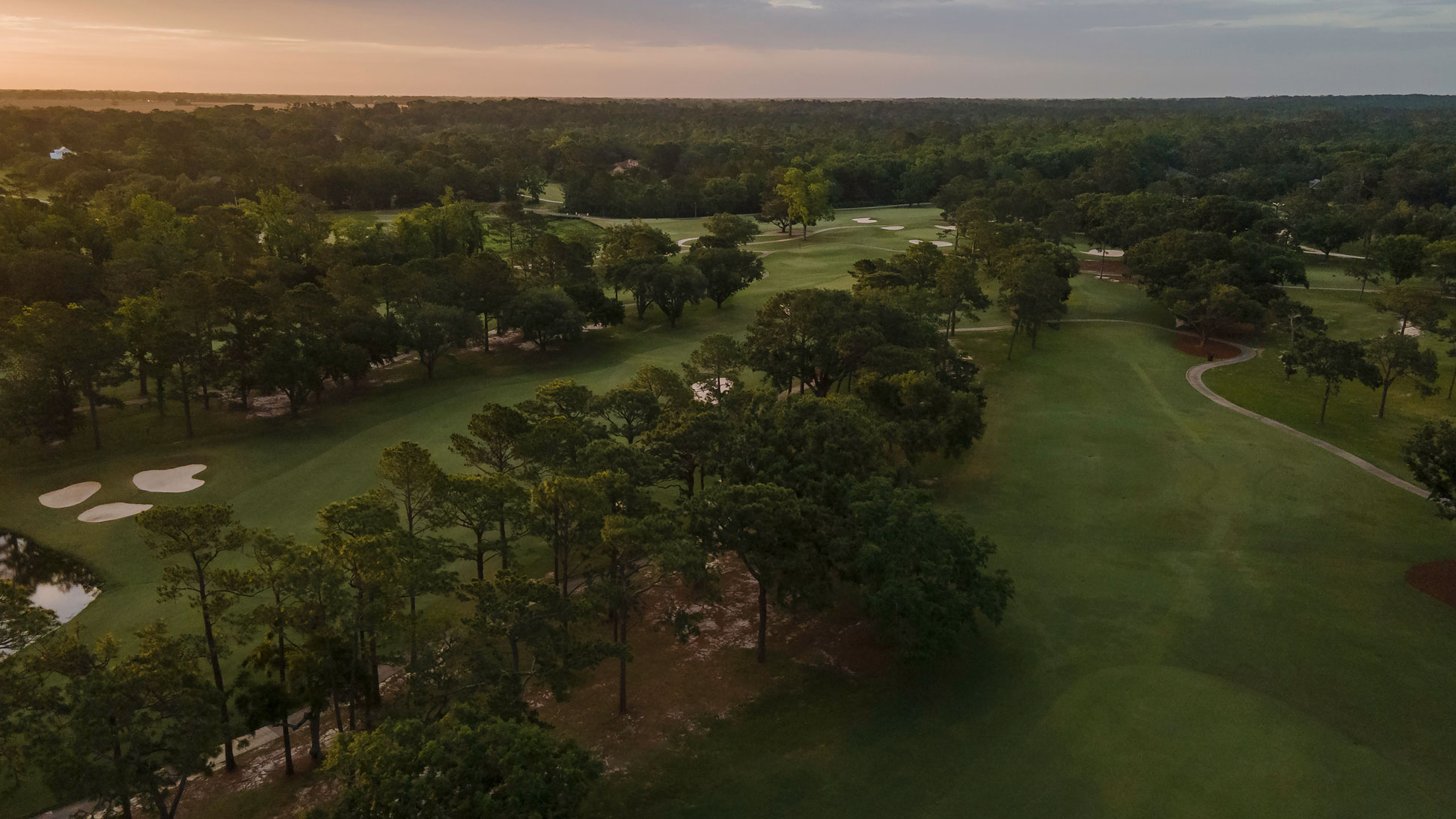 a golf course with trees and a blue sky