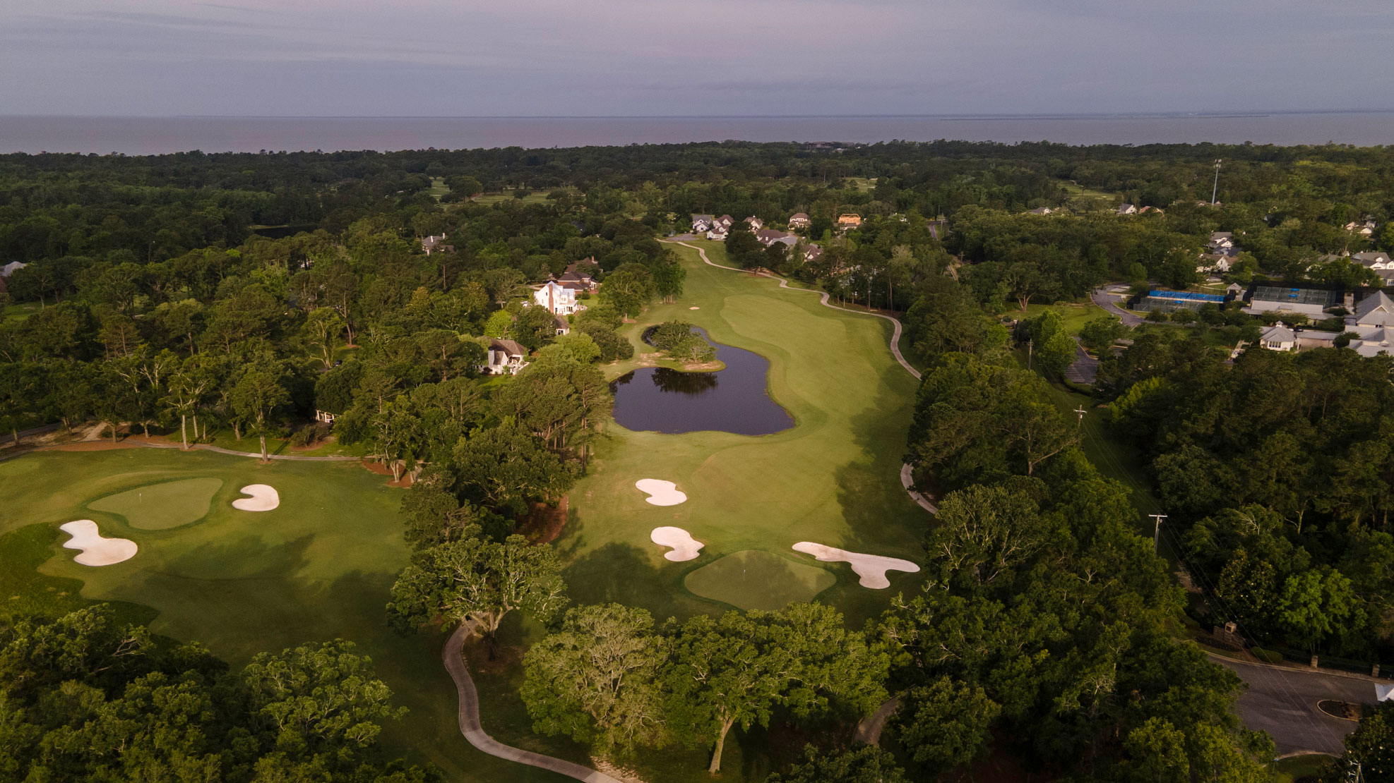 a golf course with a lake surrounded by trees