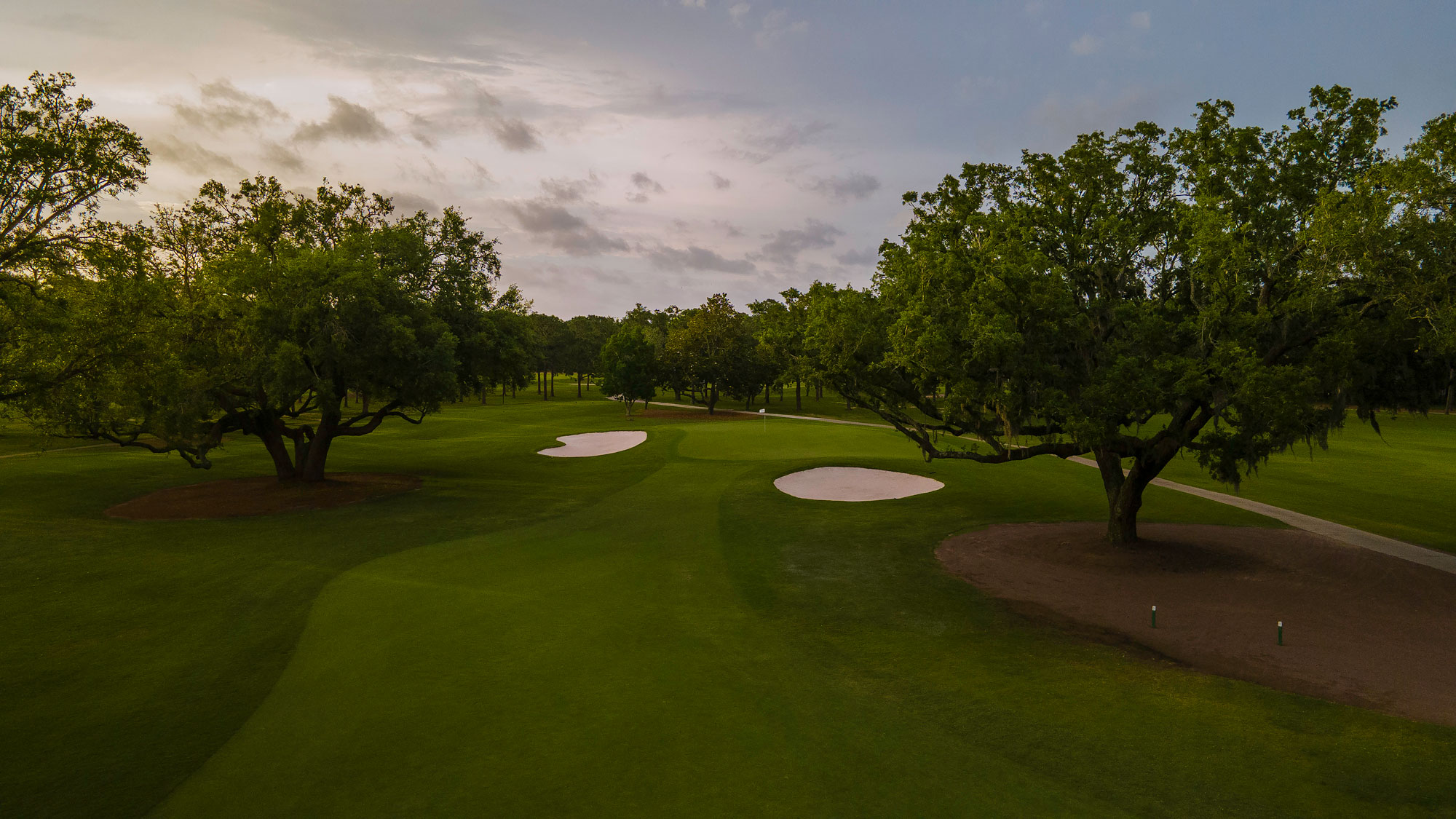 a golf course with trees and sand bunkers