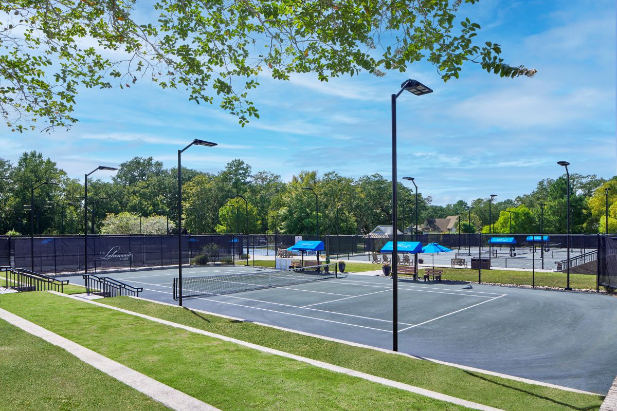 a tennis court with blue umbrellas and trees