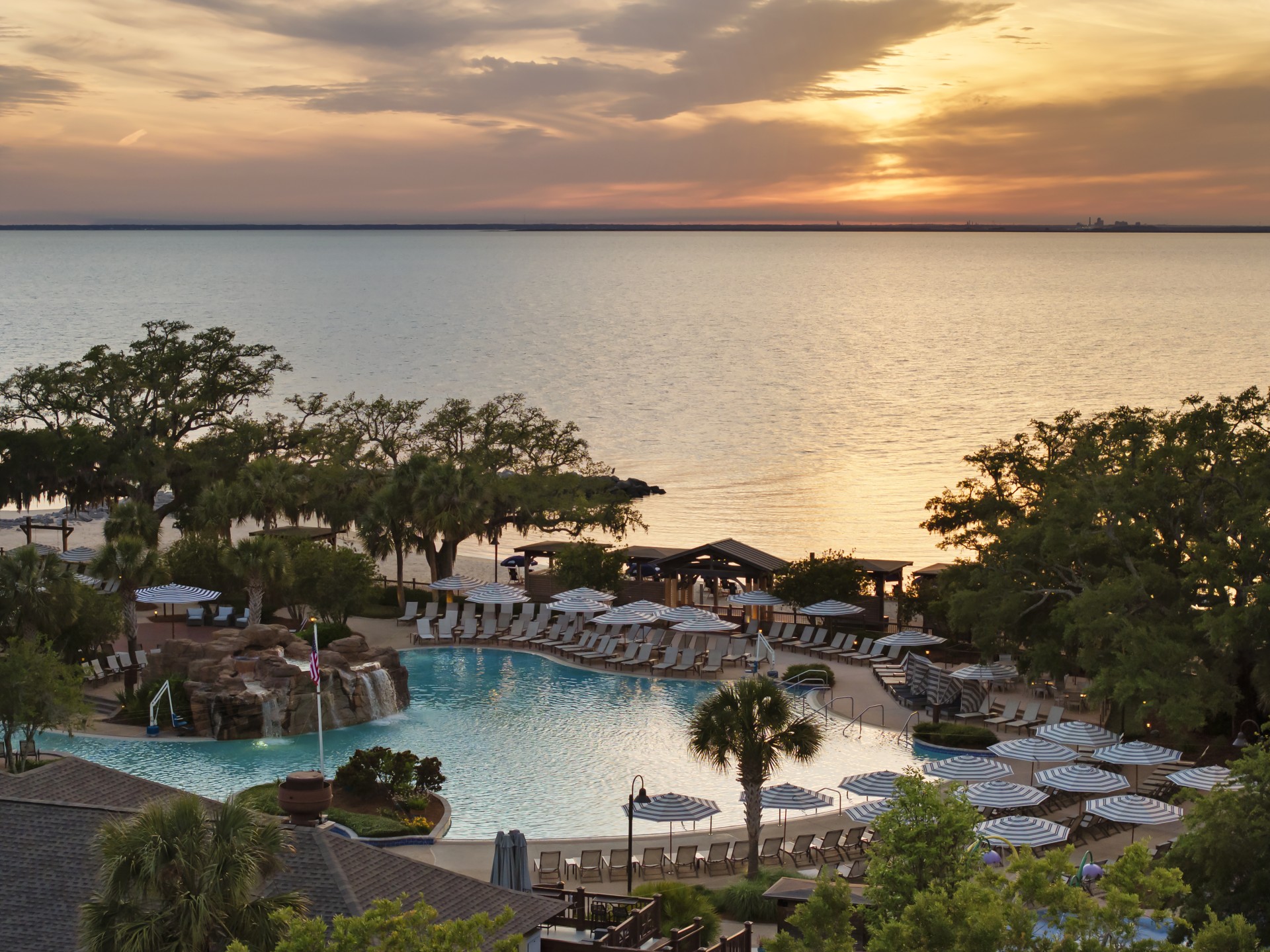 a pool with umbrellas and chairs by a body of water