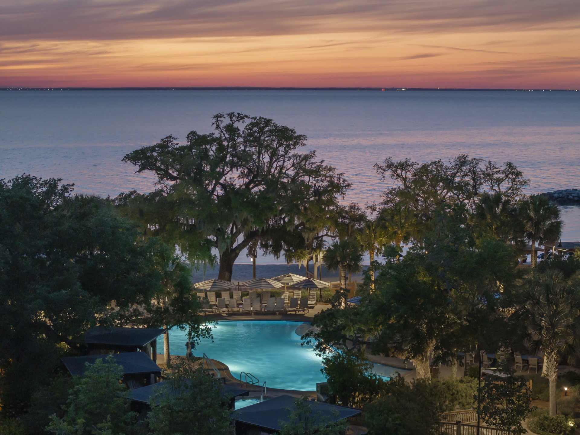 a pool with trees and a sunset