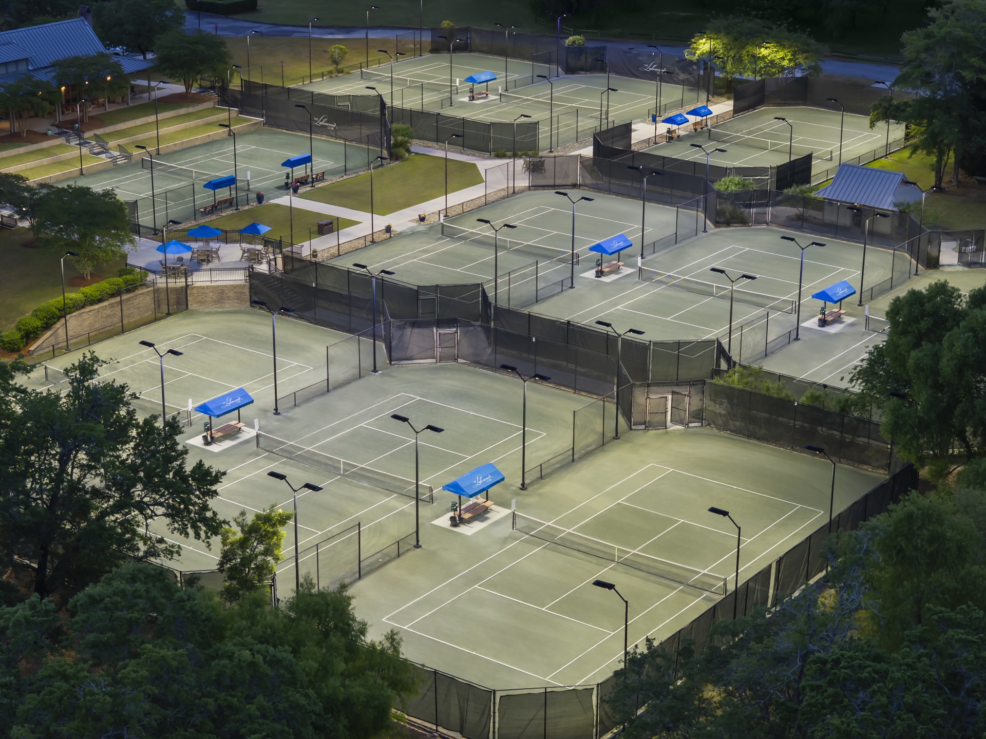 a tennis courts with lights and trees