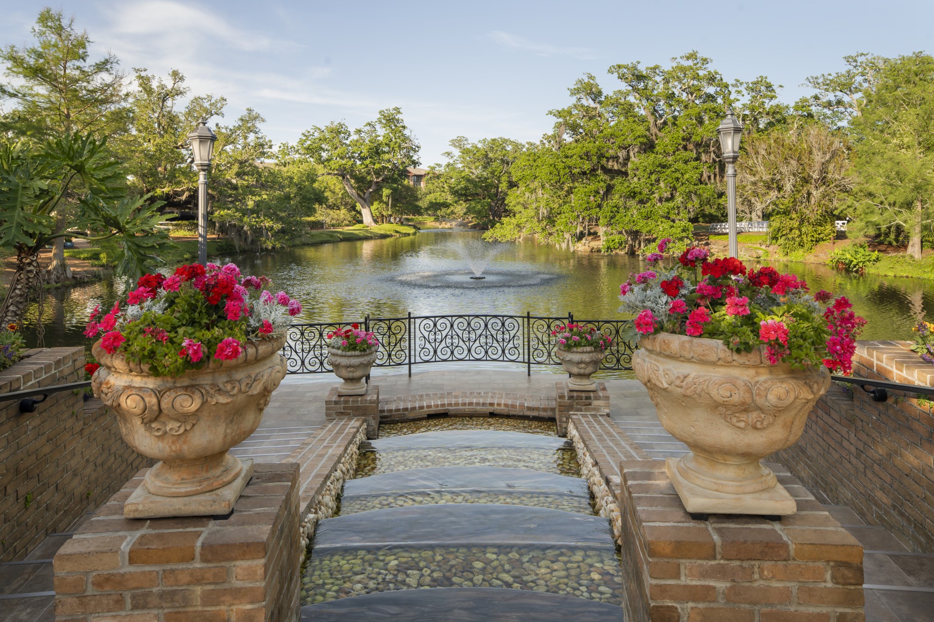 a pond with a fountain and flowers in pots