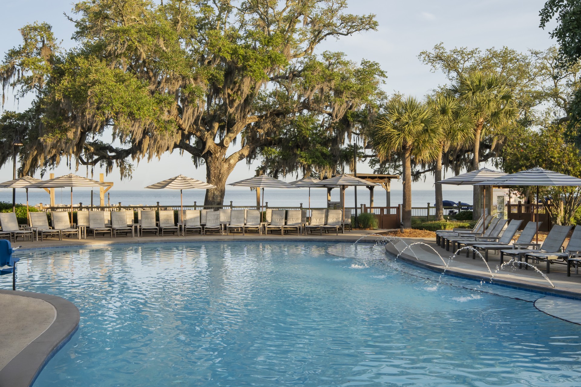 a pool with a water fountain and umbrellas