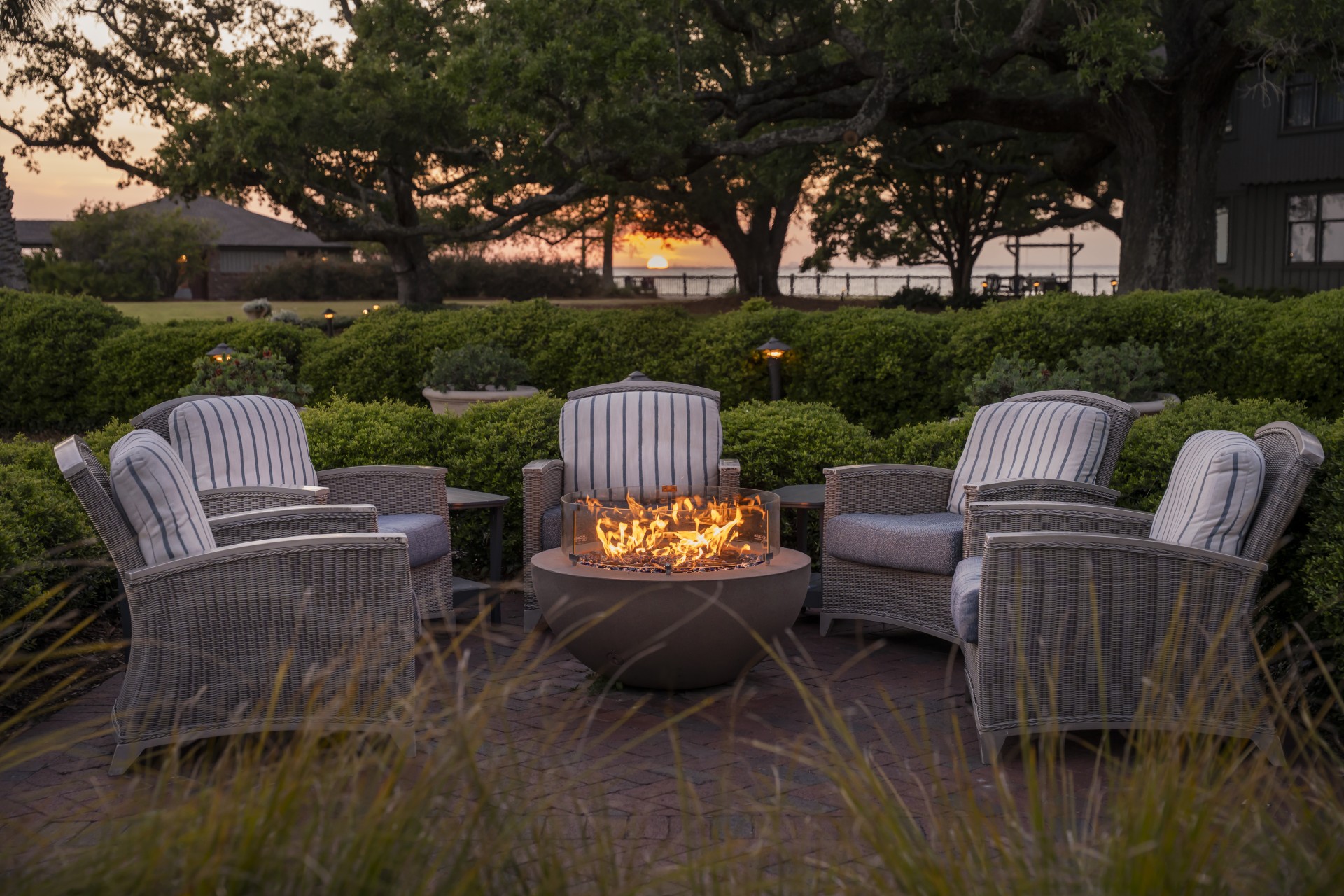 a fire pit with chairs and a sunset in the background