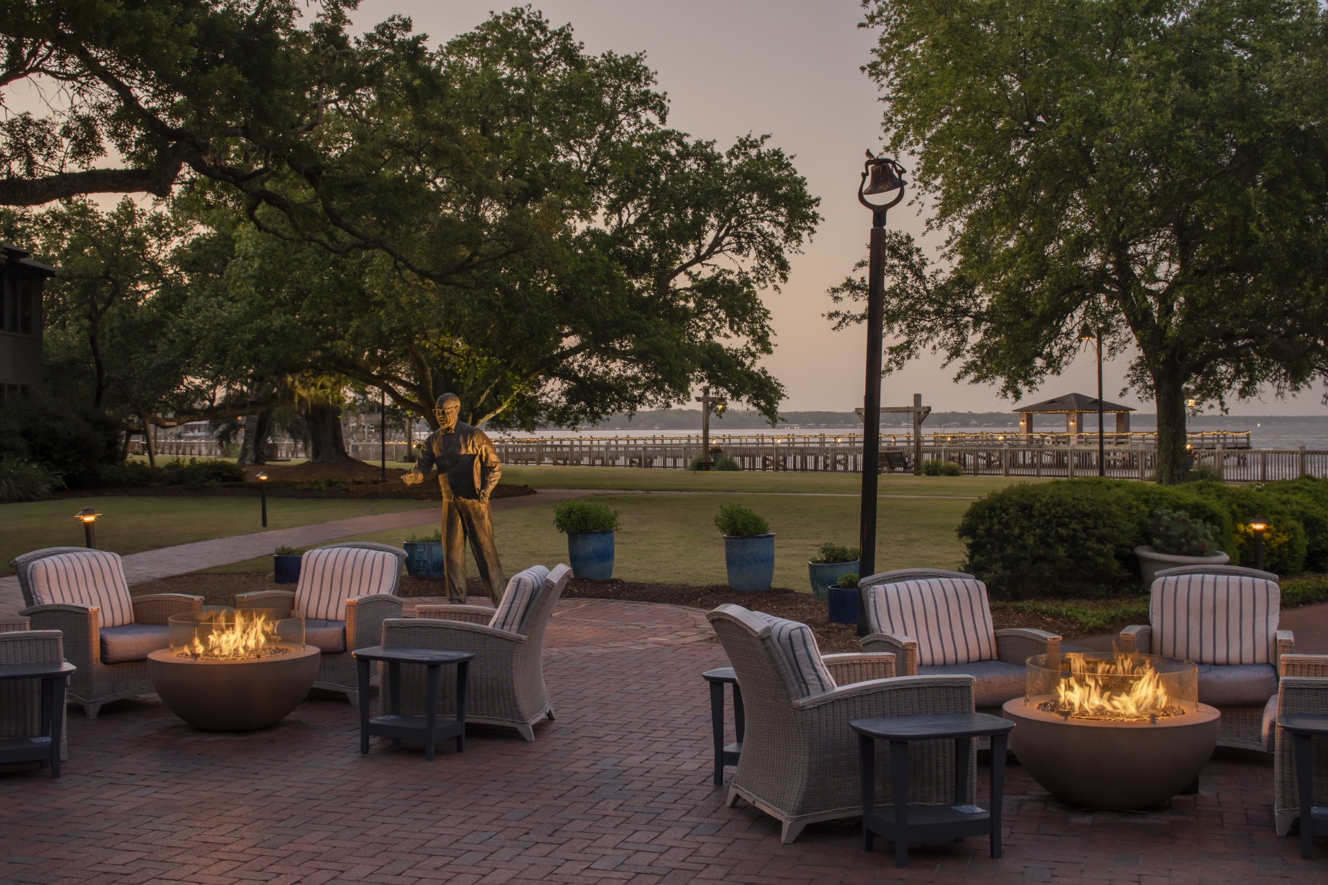 a patio with a fire pit and a statue of a man in the background