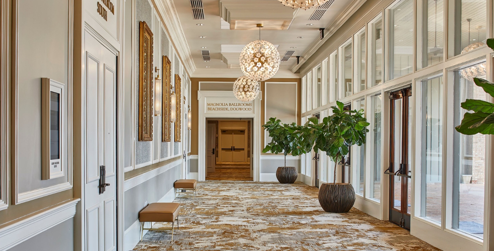 a hallway with a large chandelier and plants
