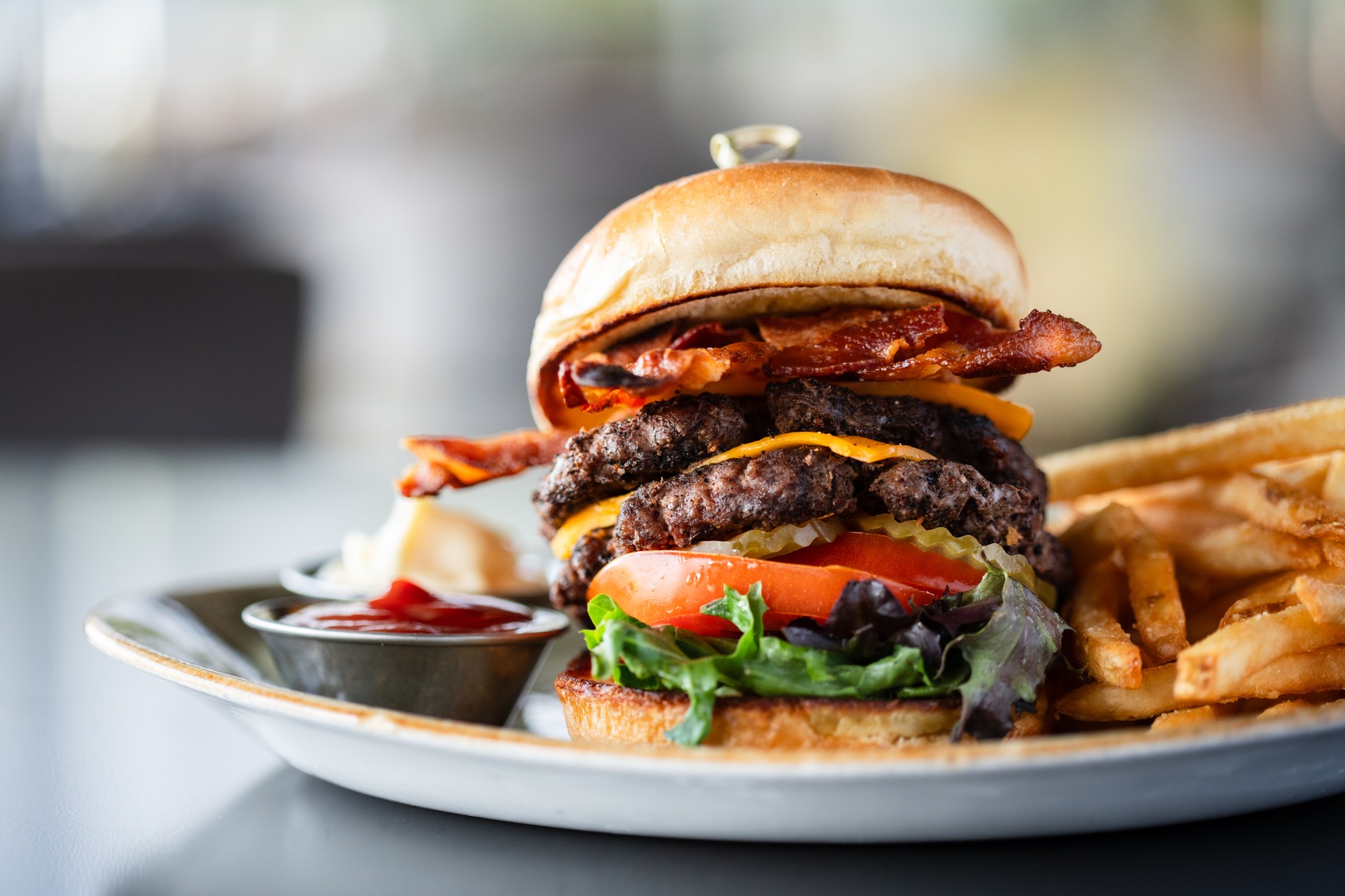 a burger with bacon and french fries on a plate