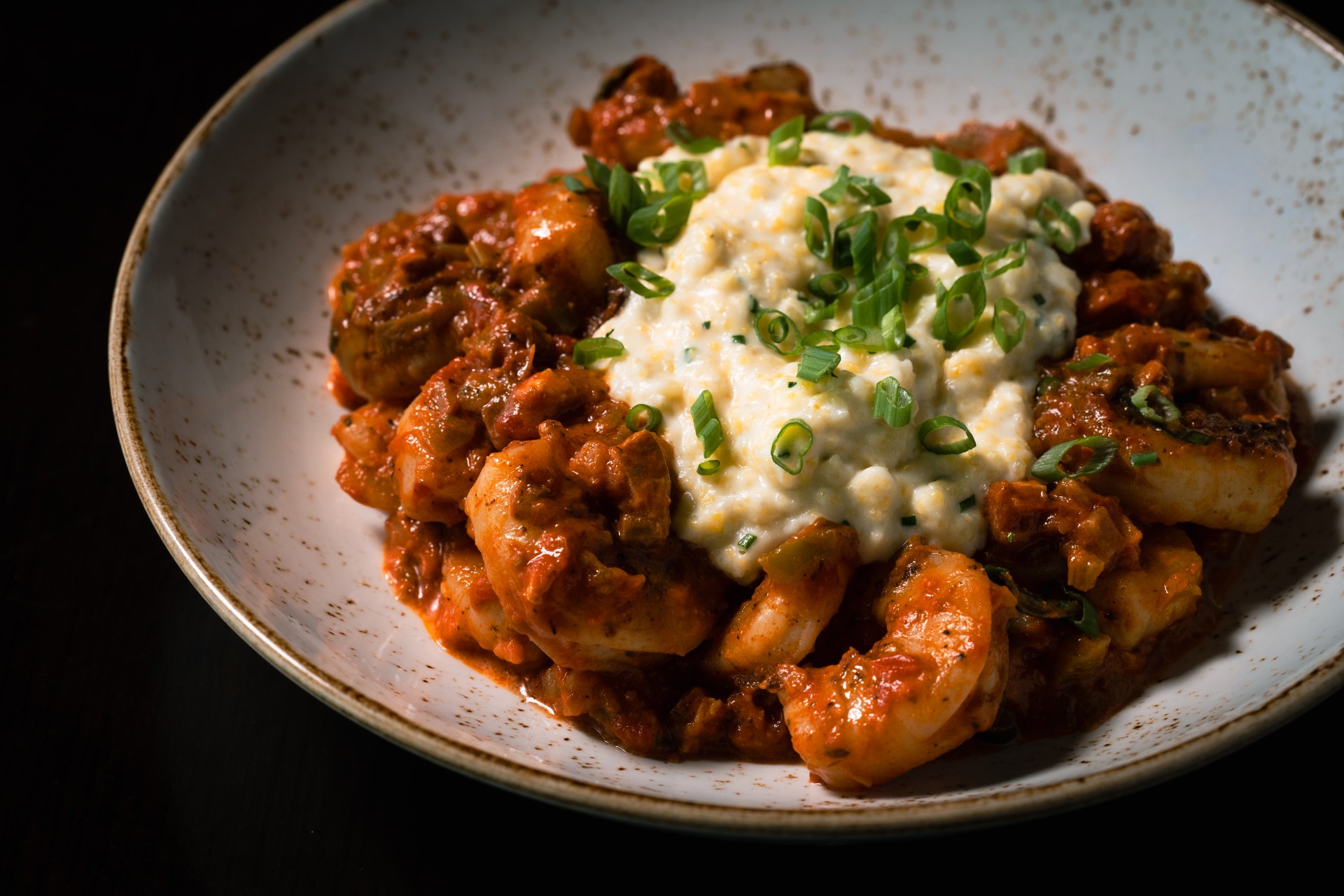 a plate of food with a white sauce and green onions