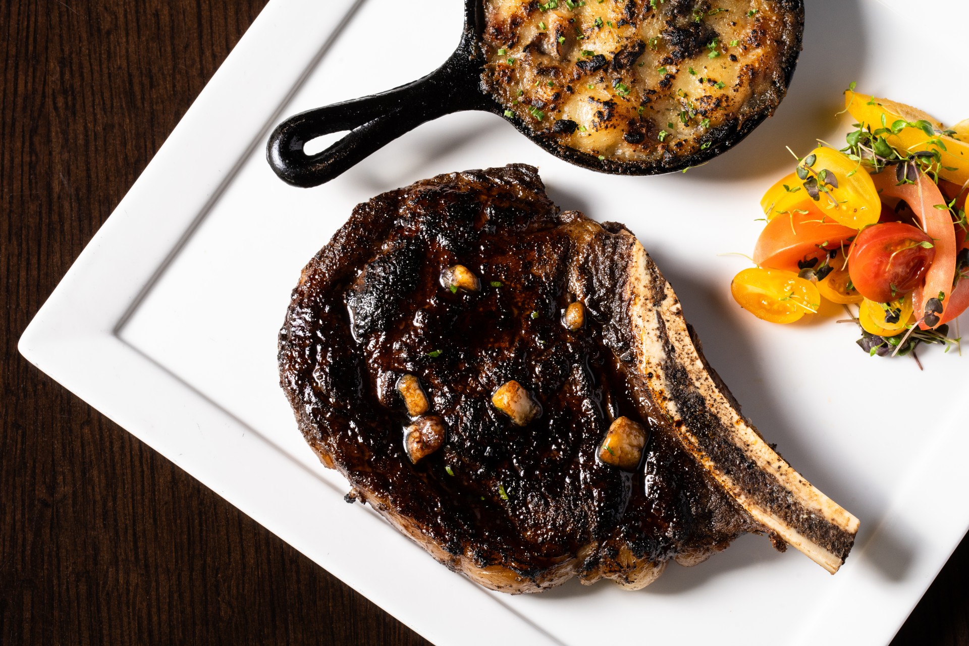 a steak and a small skillet of vegetables