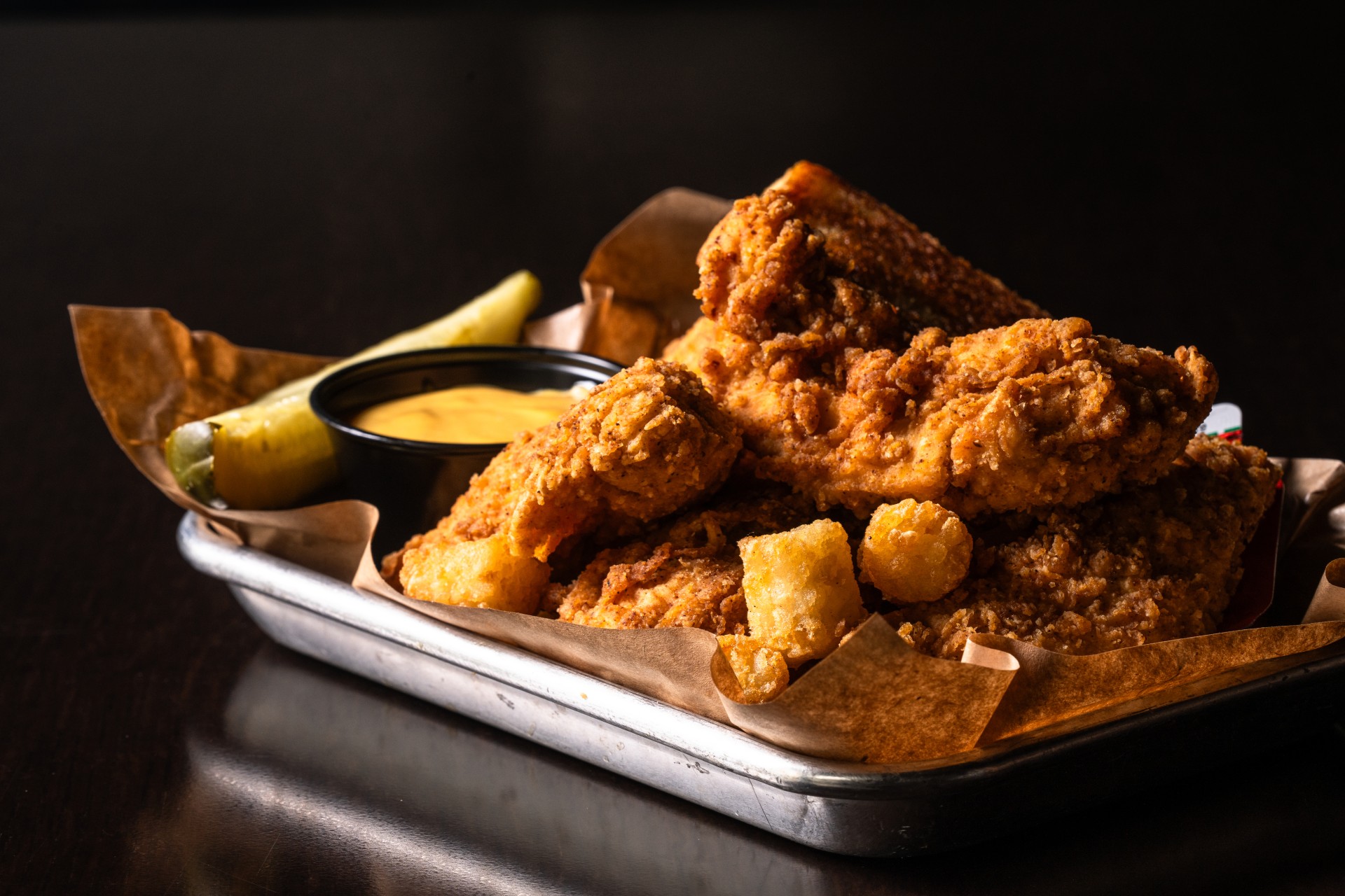 a tray of fried chicken with fries and pickles