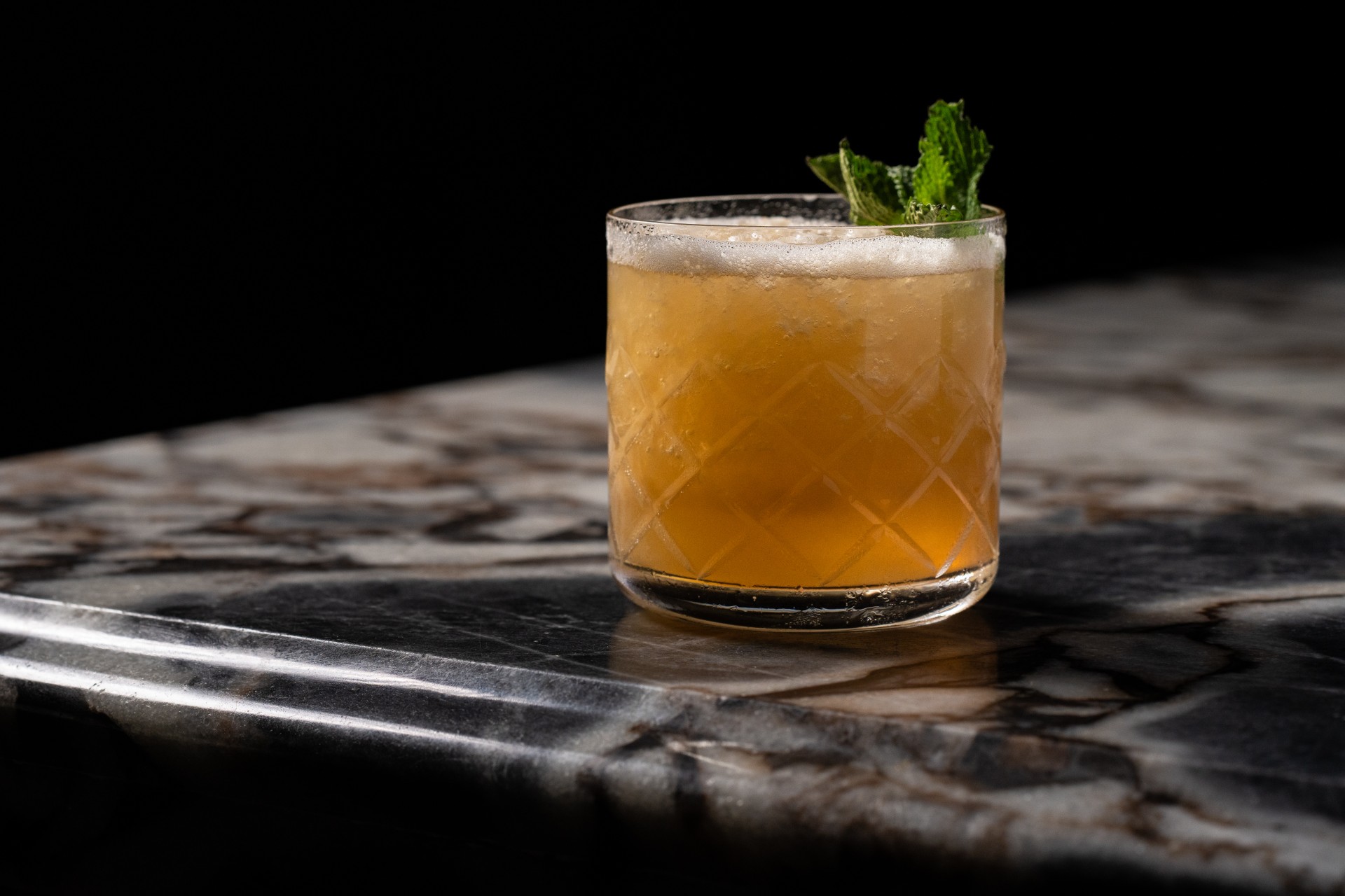 a glass of drink with a green leaf on top