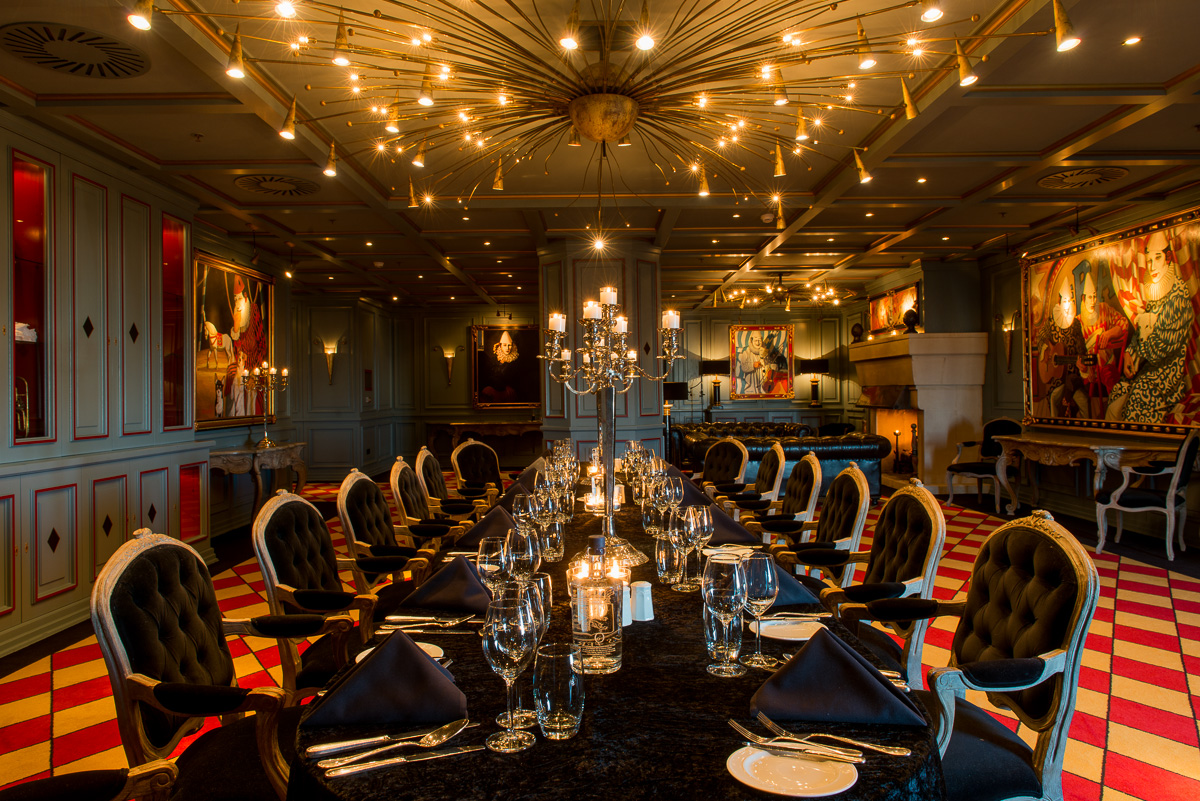 a room with a chandelier and table set for dinner