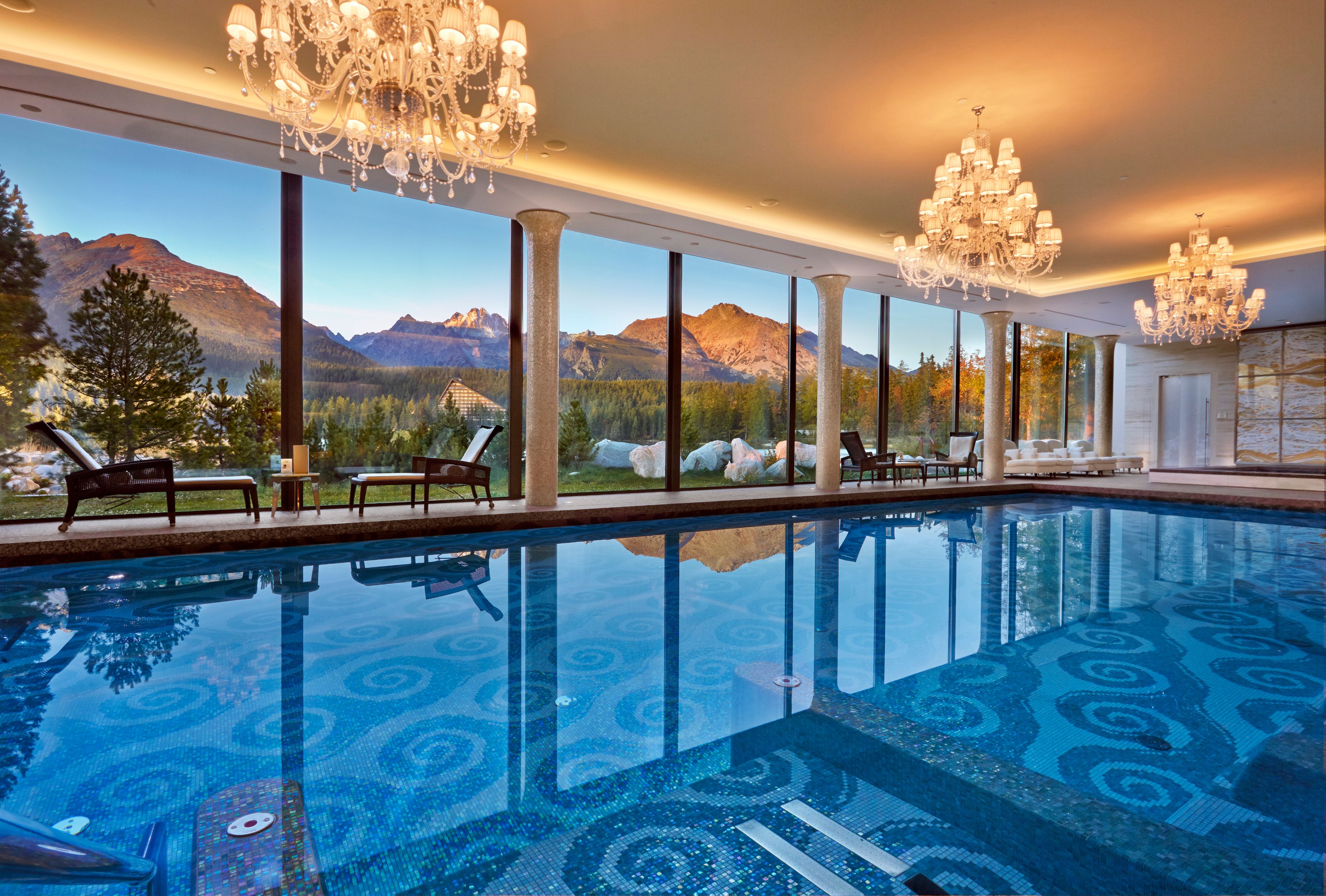 a indoor pool with a large chandelier and mountains in the background
