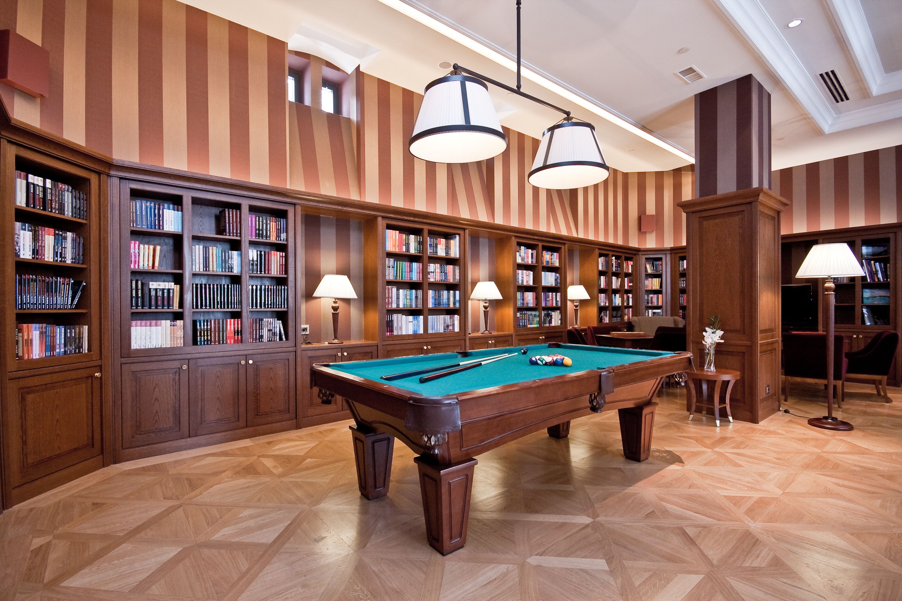 a pool table in a room with bookshelves