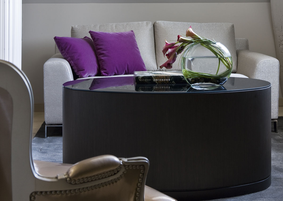 a round glass table with a vase of flowers on it