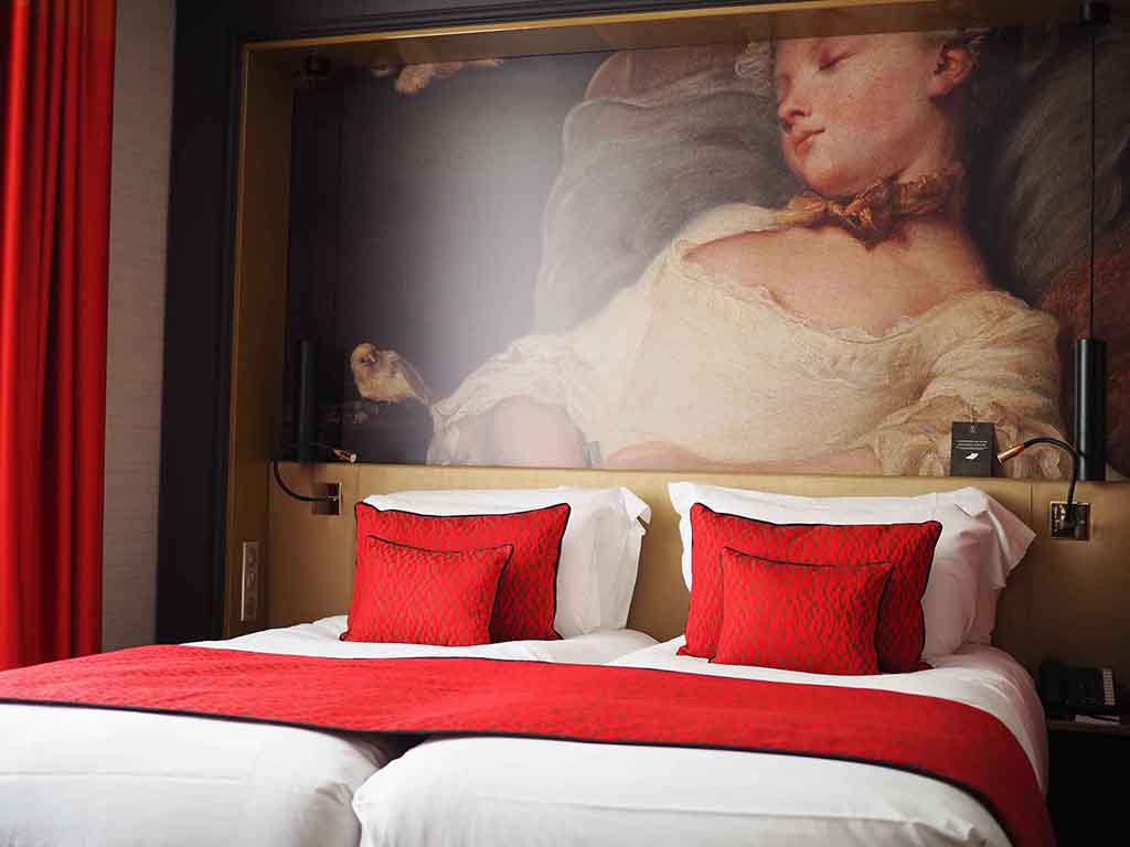 a bed with red pillows and a painting on the wall