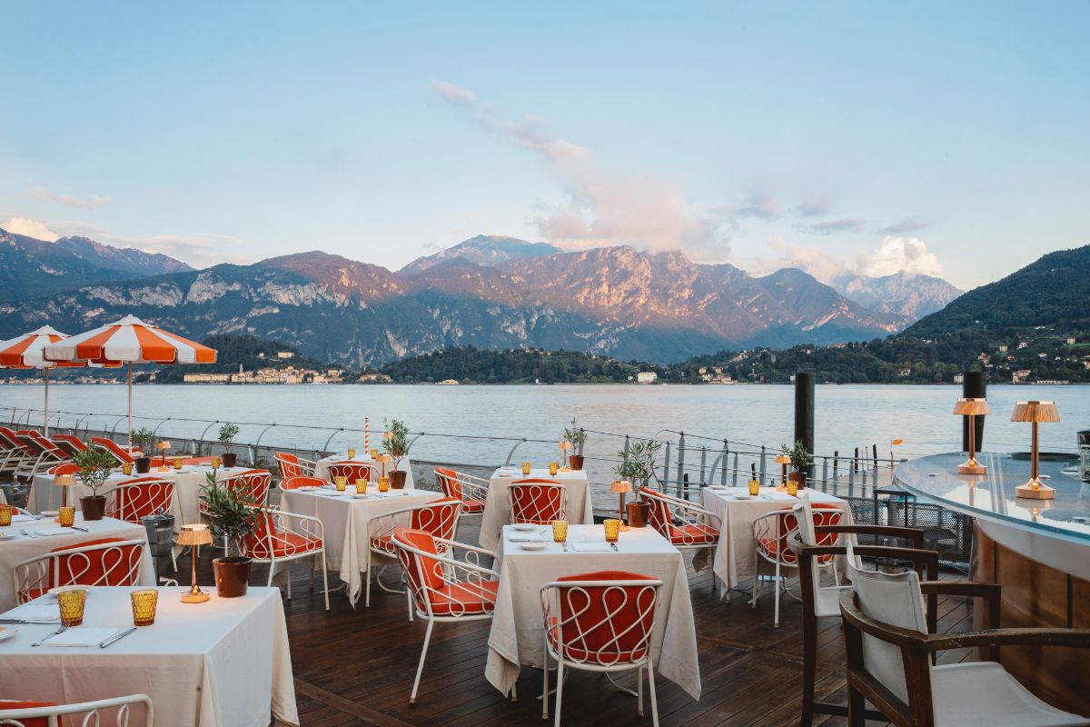 a restaurant with tables and chairs and a lake in the background