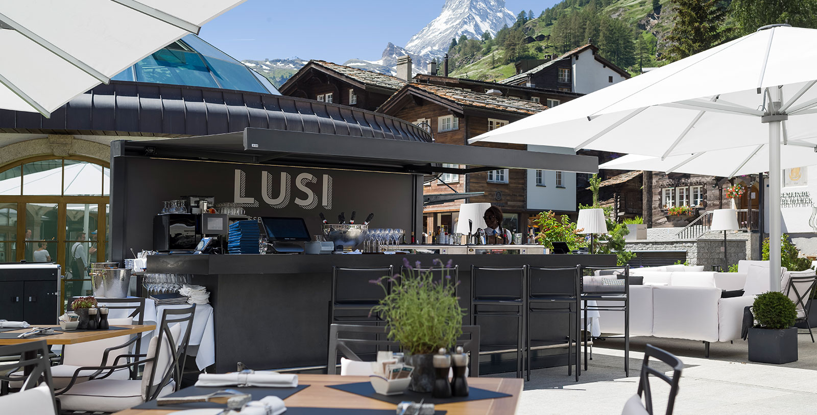 a bar outside with a woman standing behind it