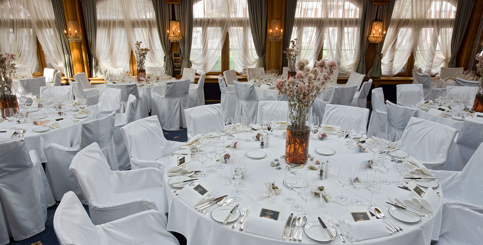 a round table with white chairs and white tablecloths
