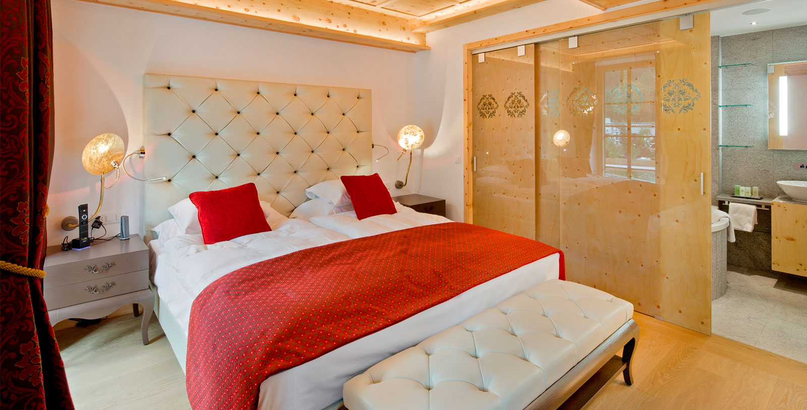a bed with red pillows and a white bed with a glass door