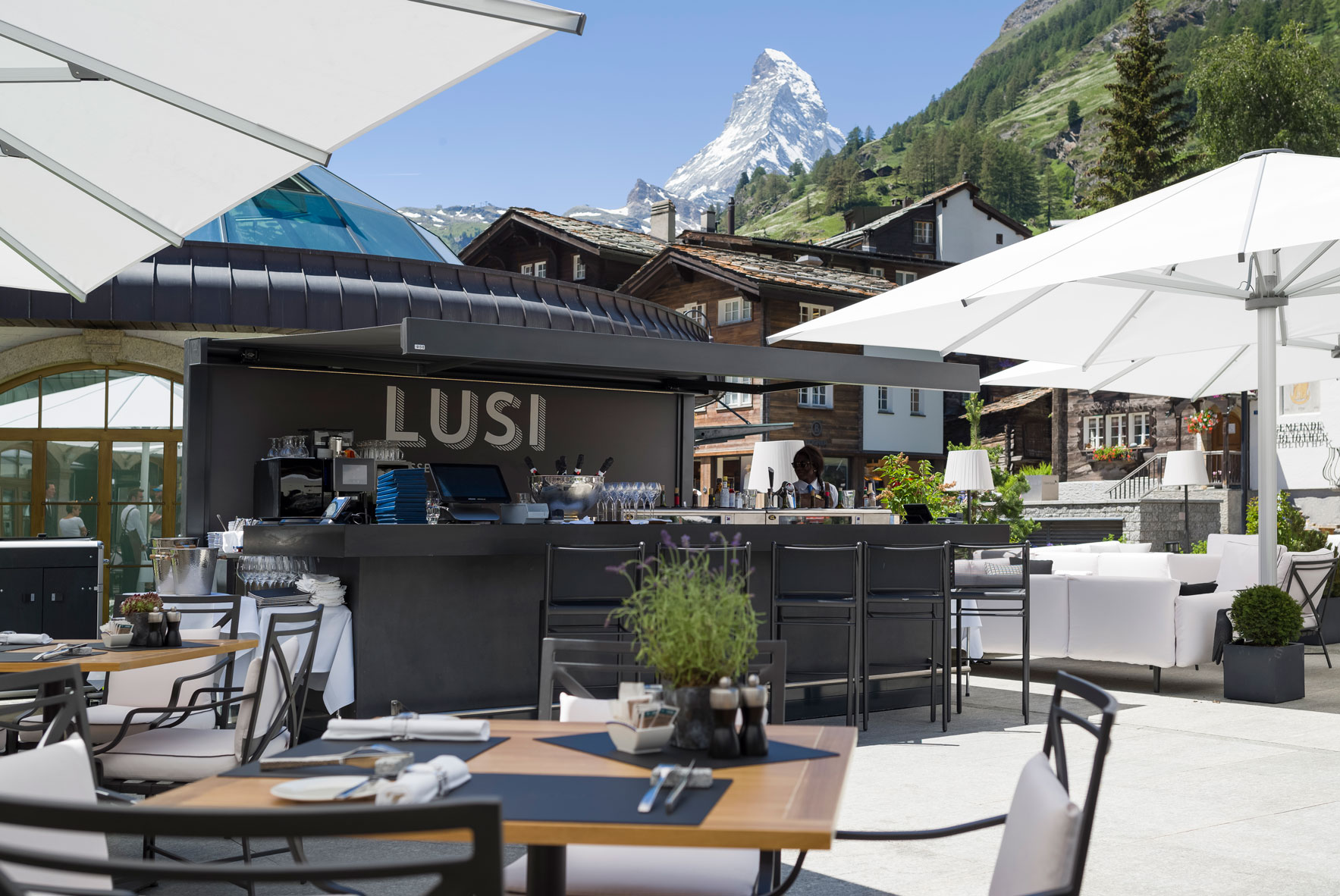 a restaurant with tables and chairs and a mountain in the background