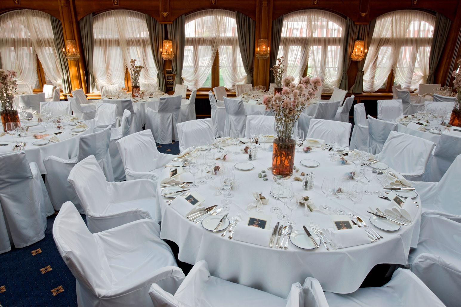 a round table with white chairs and white tablecloths