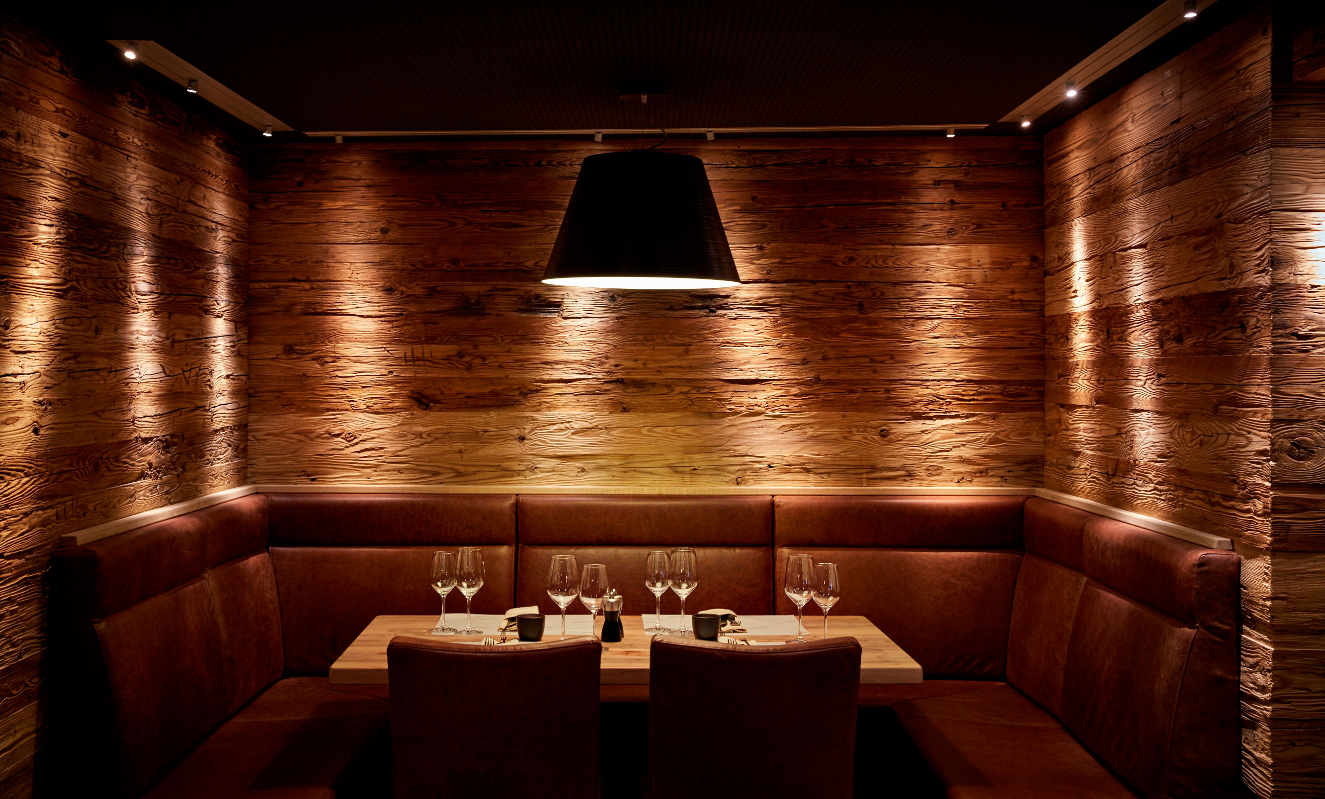 a table with wine glasses and a wood wall