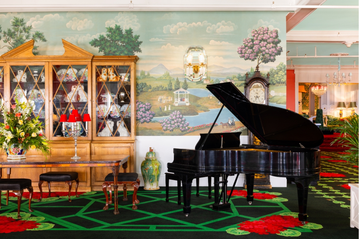 a piano in a room with a china cabinet and a vase
