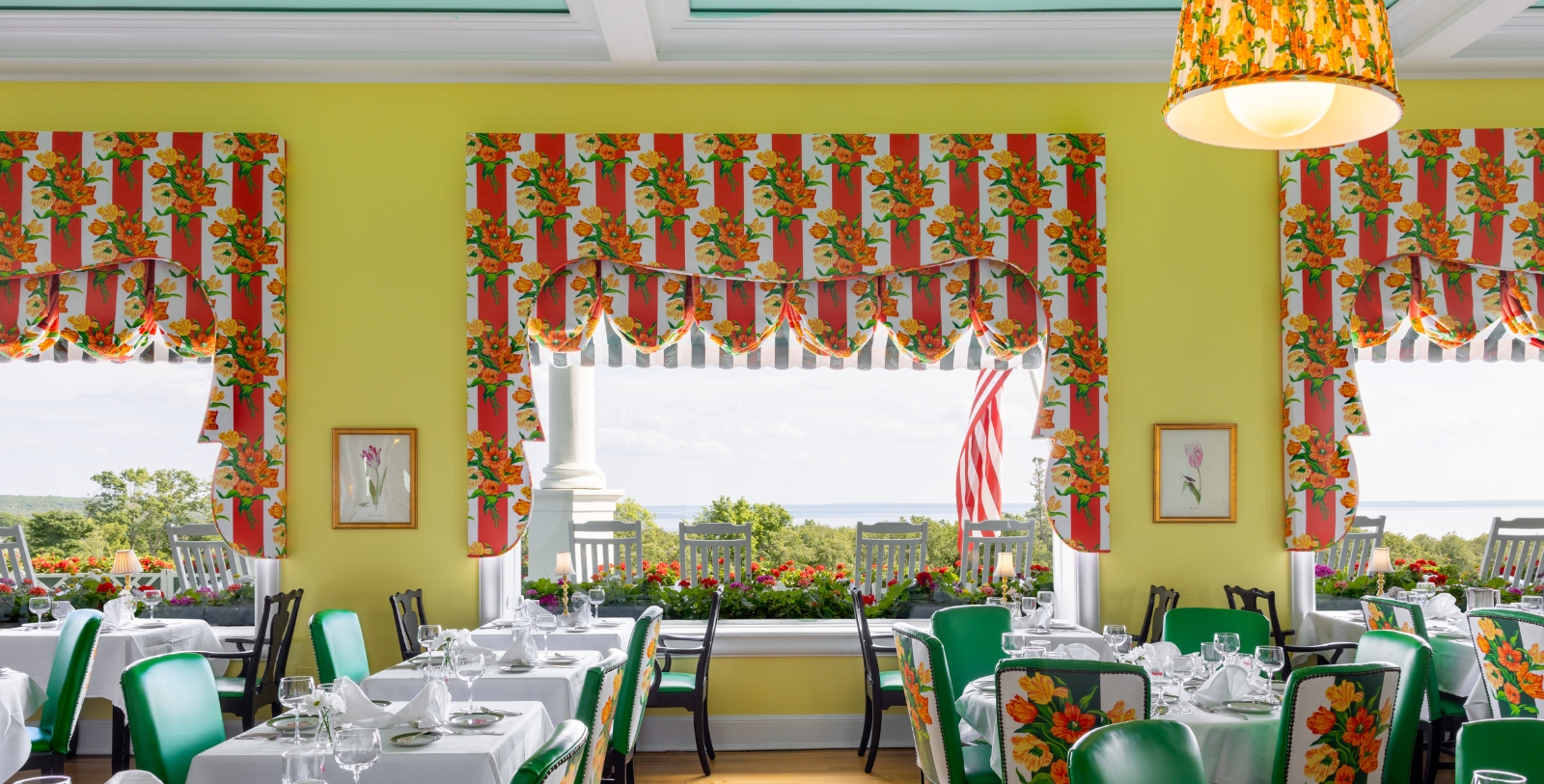 a room with tables and chairs and a window with a view of the ocean
