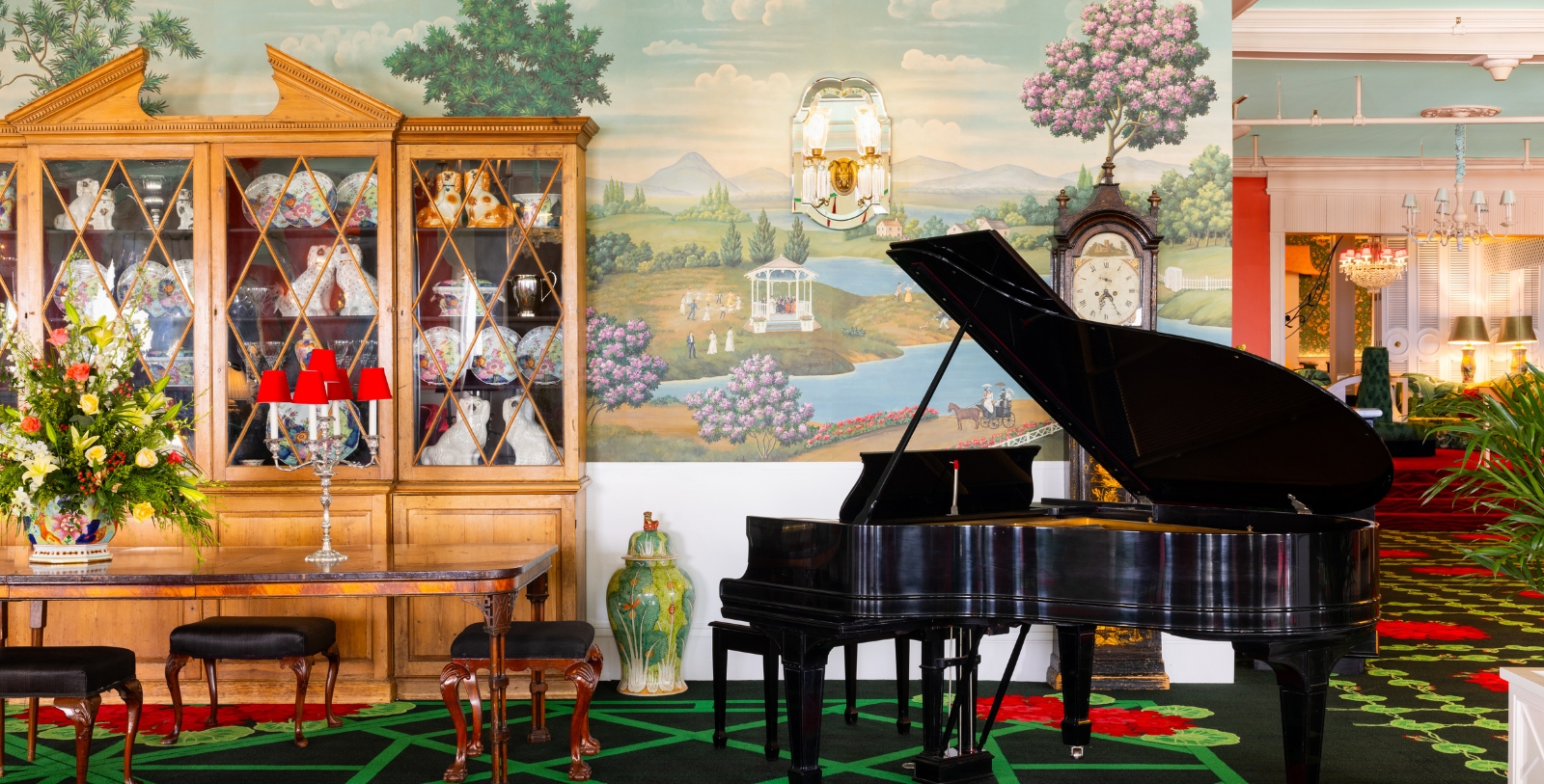 a piano in a room with a china cabinet and a wallpaper