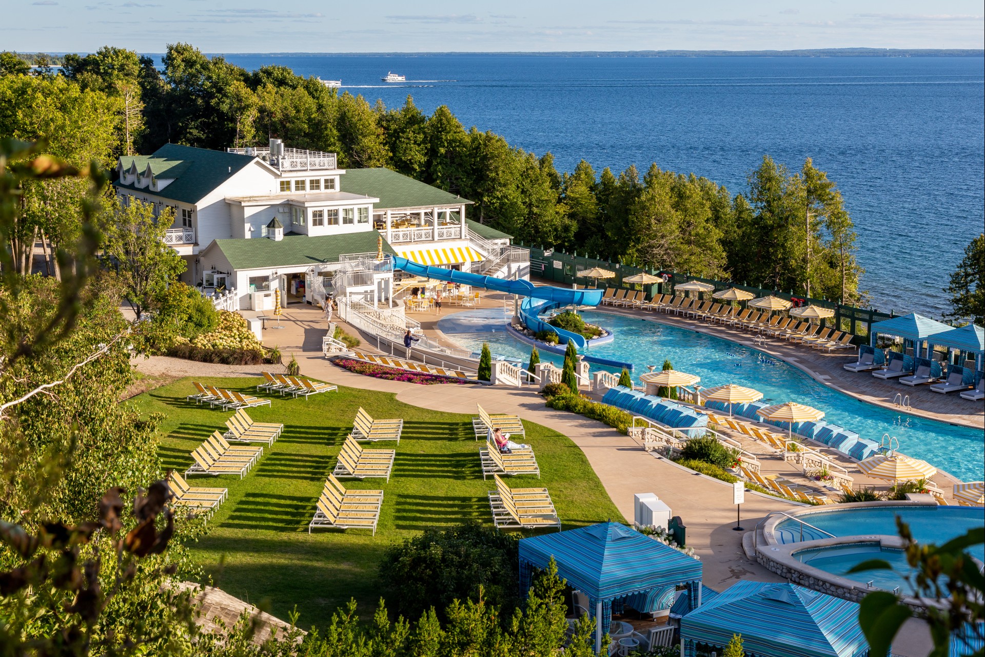 a swimming pool with a slide and a building with trees and a body of water
