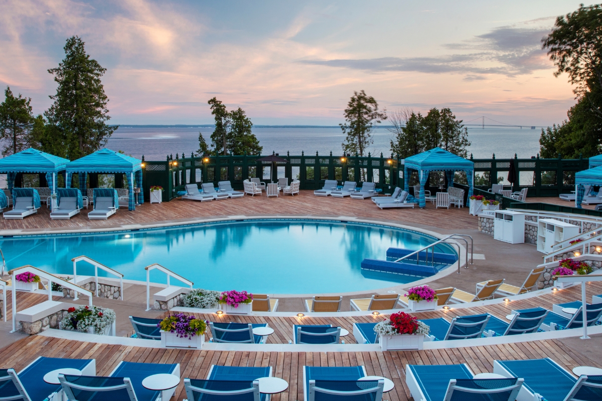 a pool with chairs and a deck with a view of the ocean