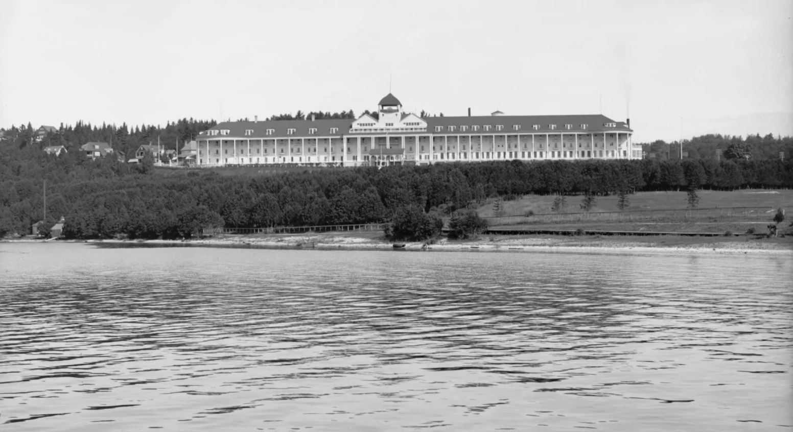 a large building with a large roof and trees next to a body of water