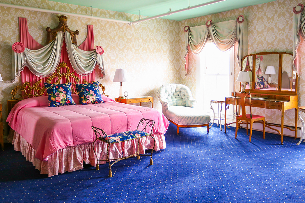 a bedroom with a pink bed and blue carpet