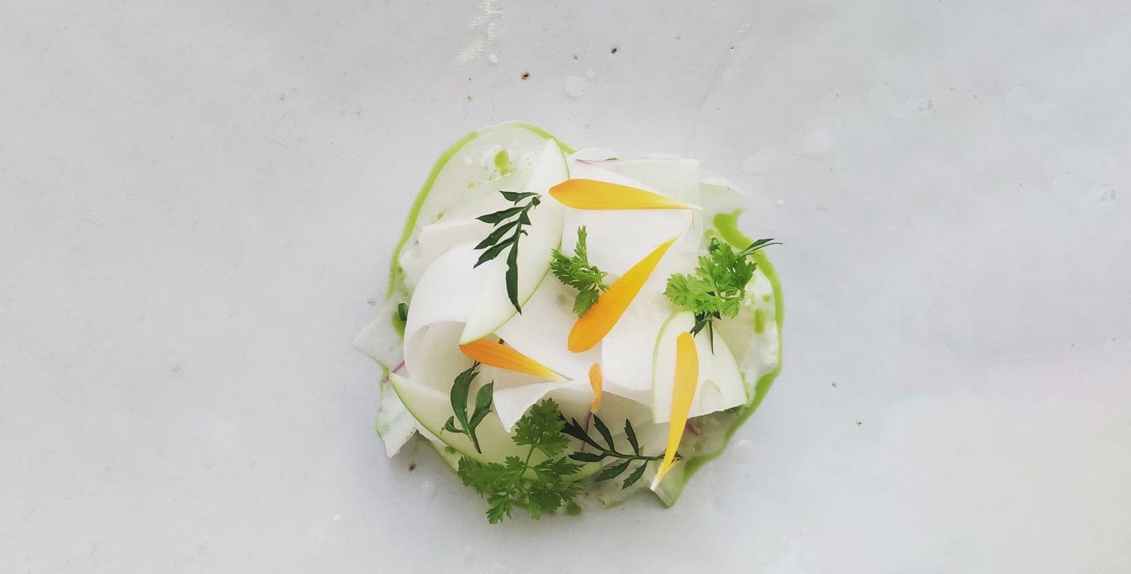 a plate of food with leaves and a flower