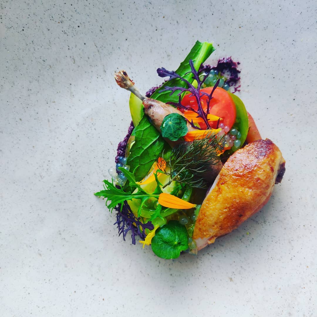 a chicken leg with vegetables on a white surface