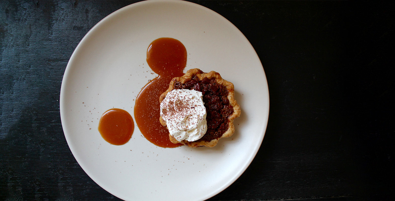 a pie with whipped cream and sauce on a white plate