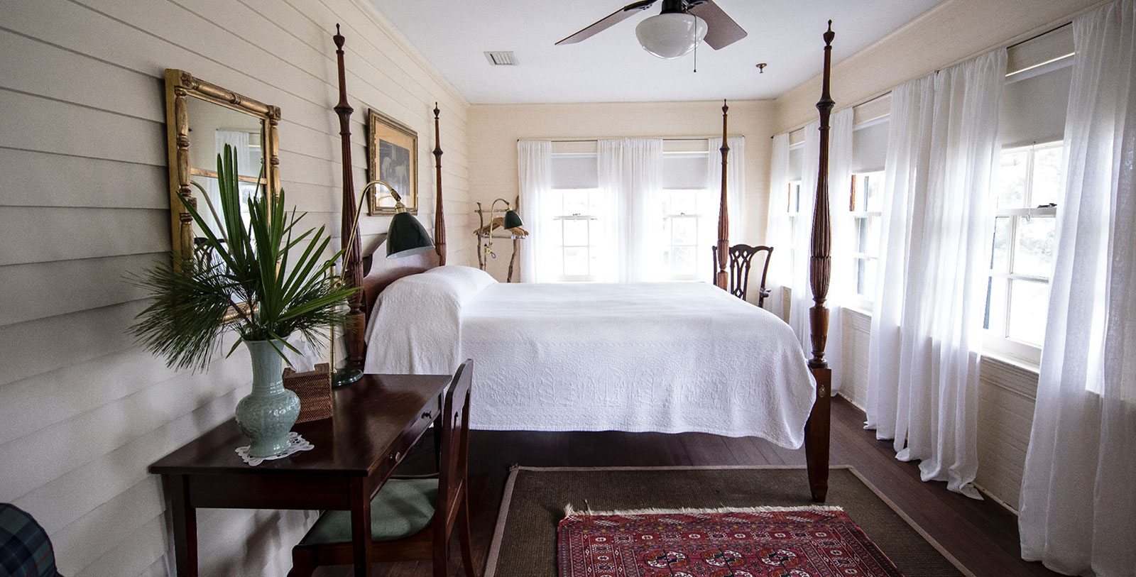 a bedroom with a four poster bed and a fan