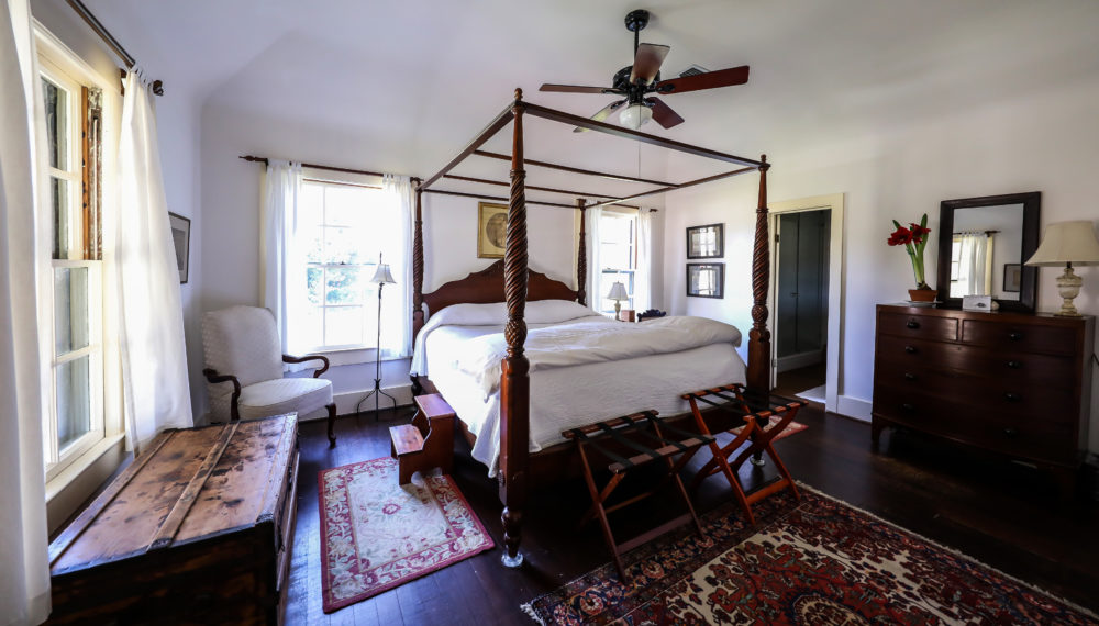a room with a four poster bed and a fan