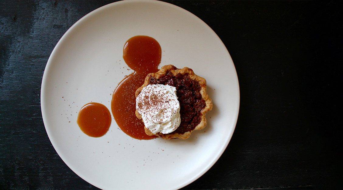 a pie with whipped cream and sauce on a white plate
