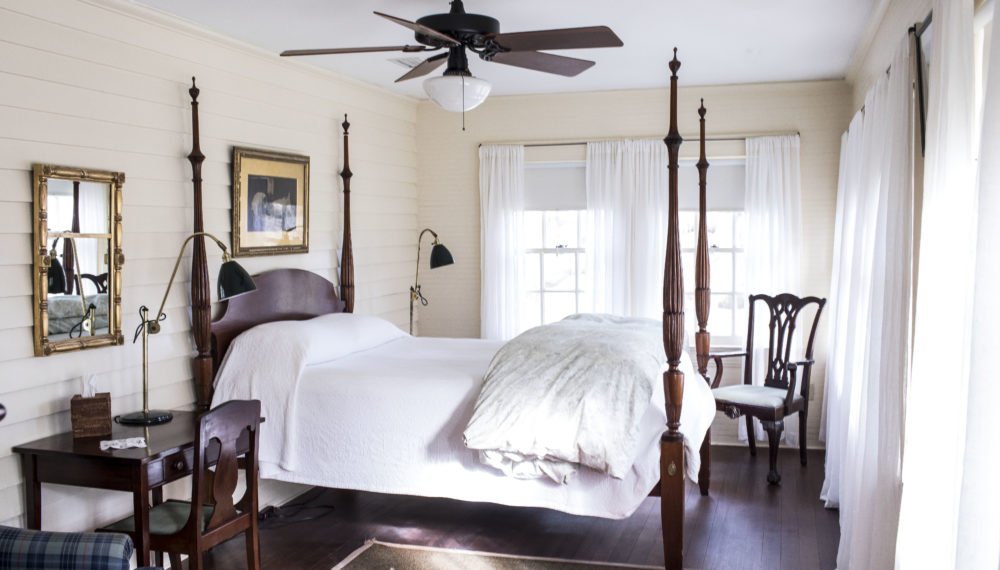 a bedroom with a four poster bed and a ceiling fan