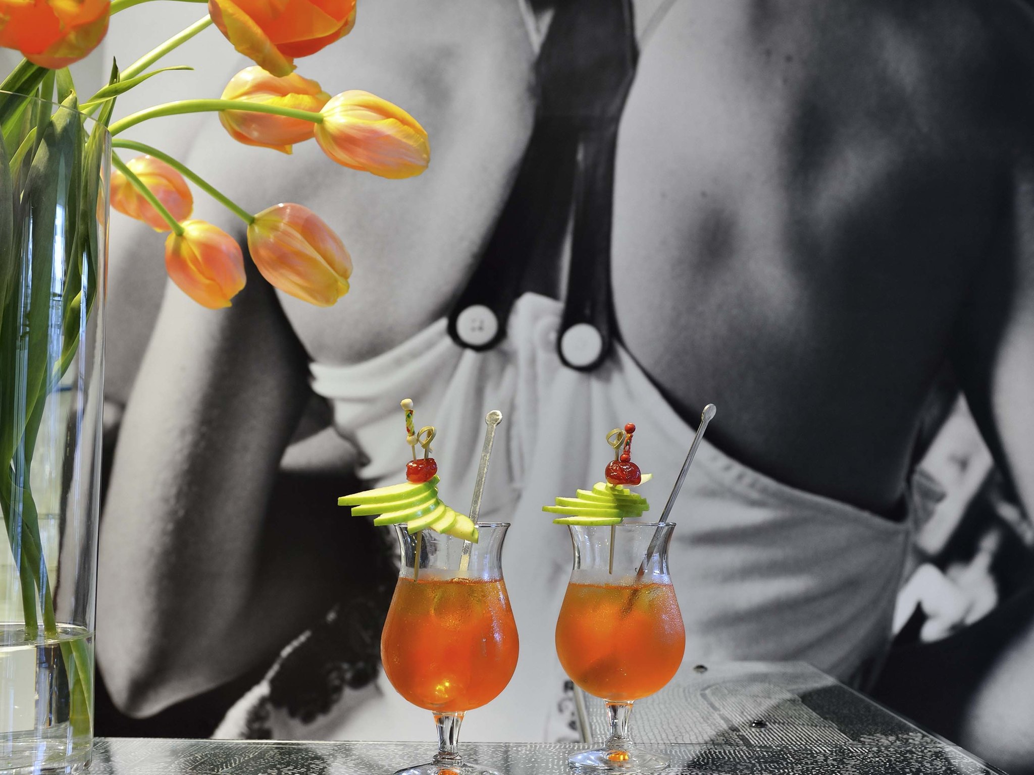 two glasses with orange liquid and fruit on them